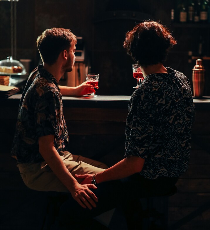 two gay men sitting at a bar while touching